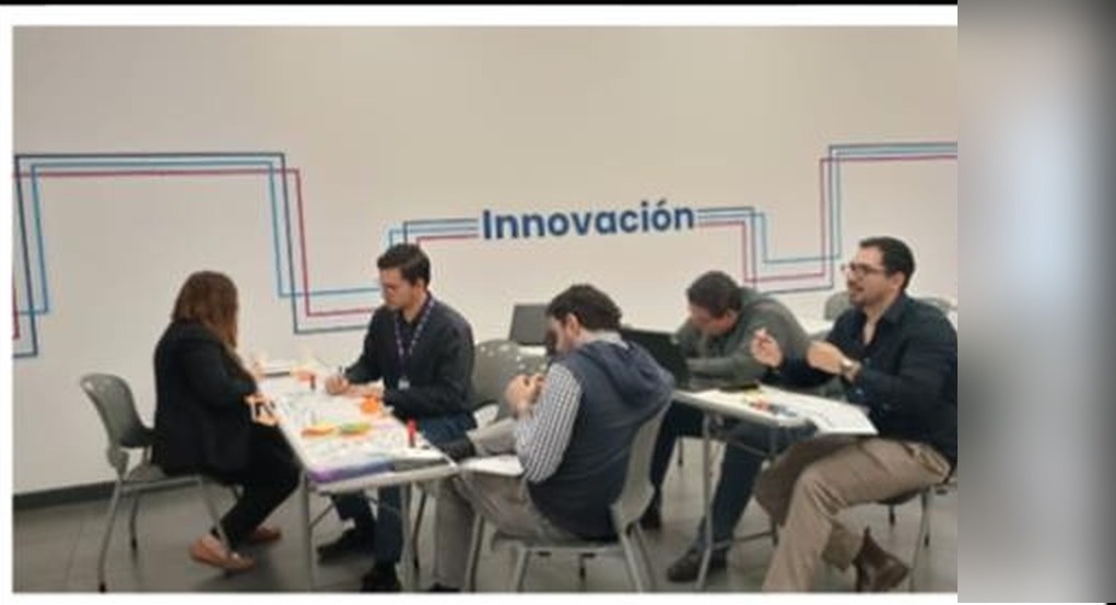 Equipos multidisciplinarios trabajando en mesas durante el workshop de ideación.